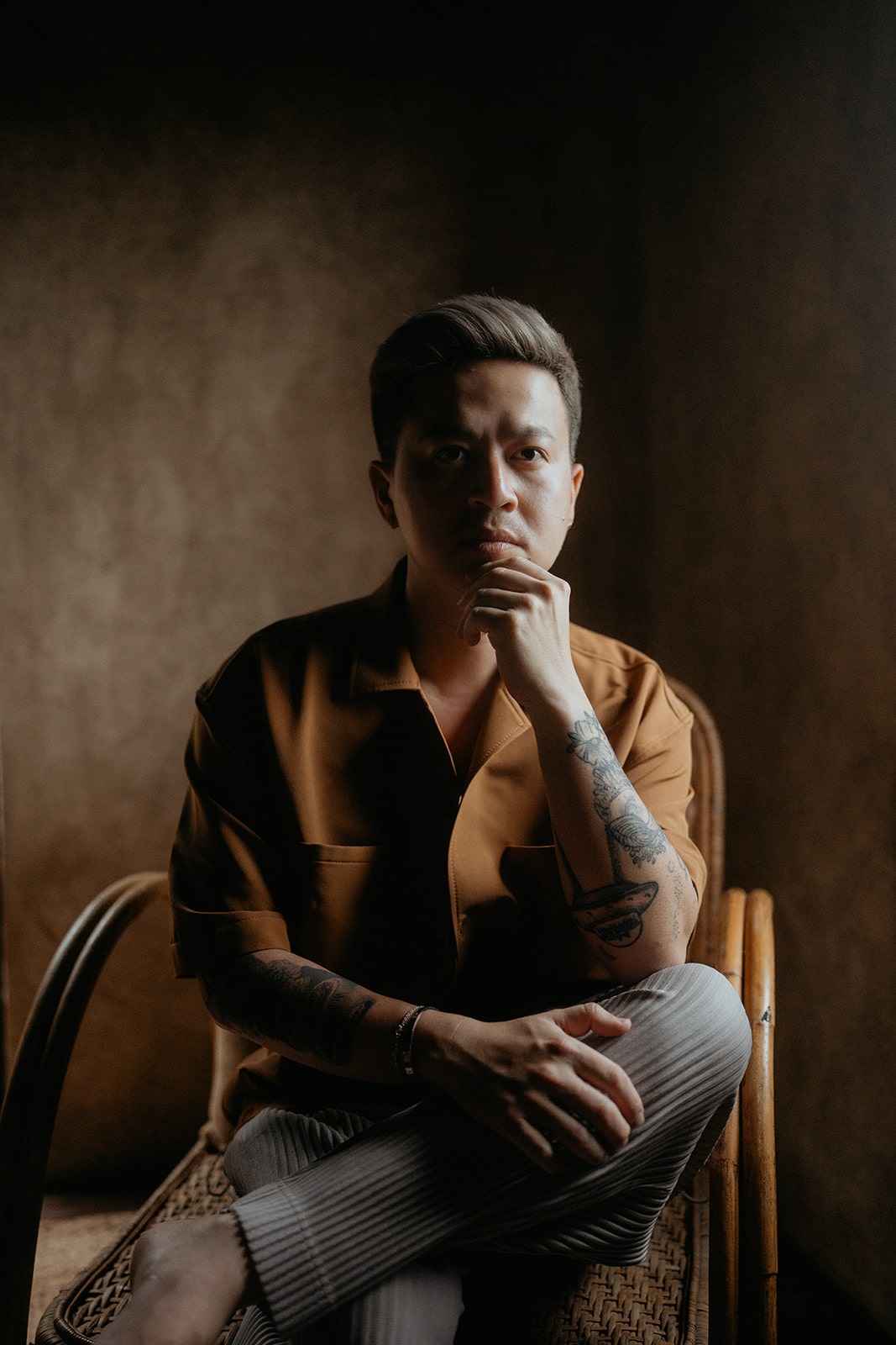 Henry Tieu, a Washington intimate wedding and elopement photographer, sits in a chair posing for the camera.