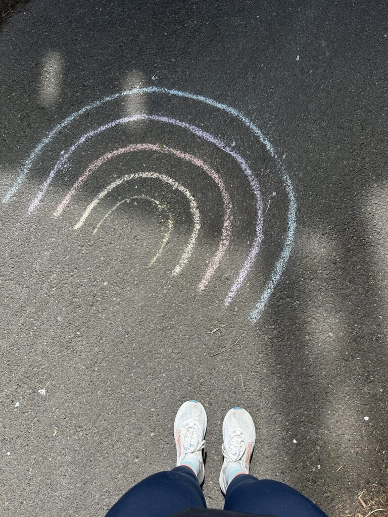 Runner looks down at rainbow chalk art during a road run.