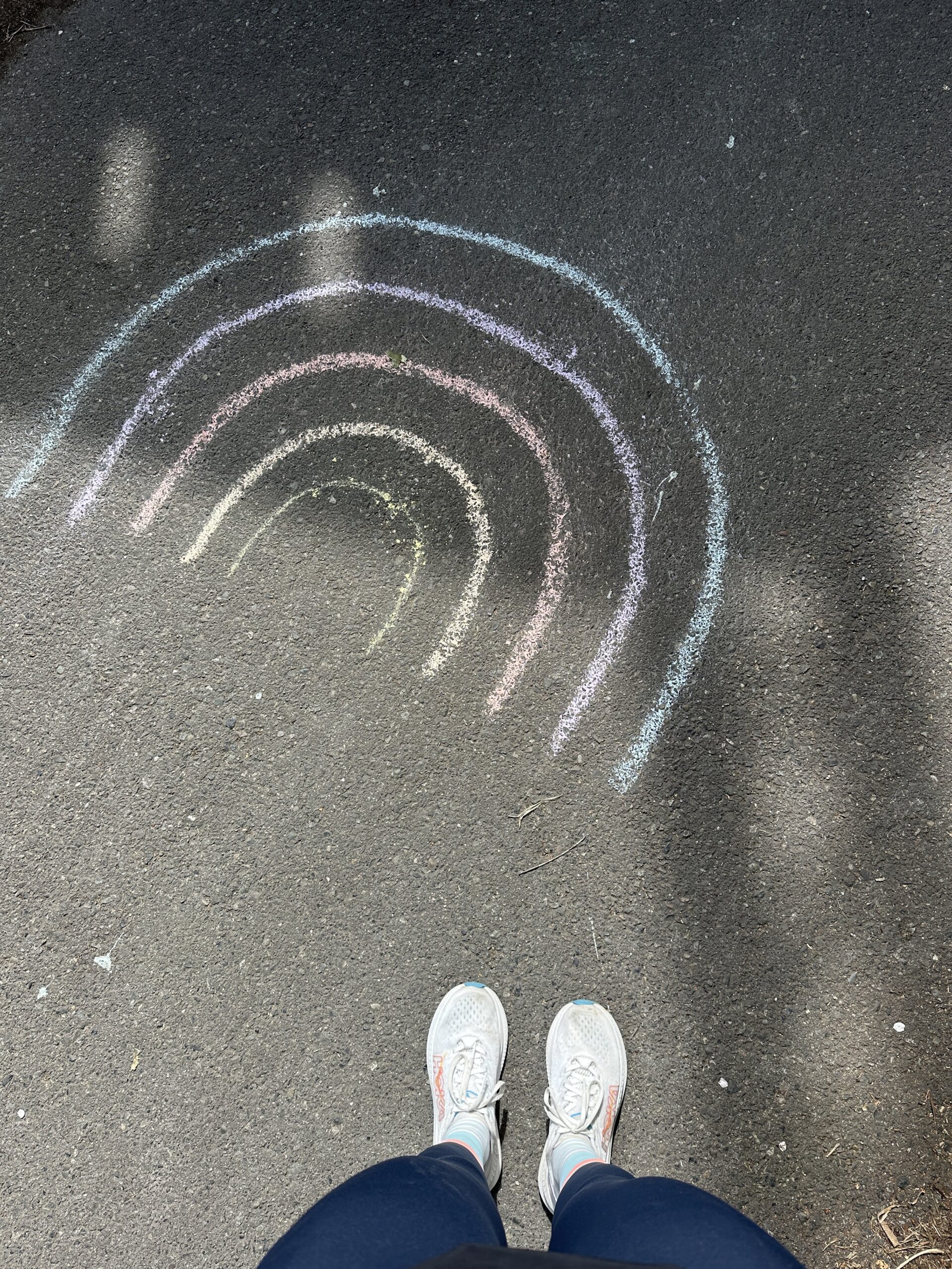 Runner looks down at rainbow chalk art during a road run.