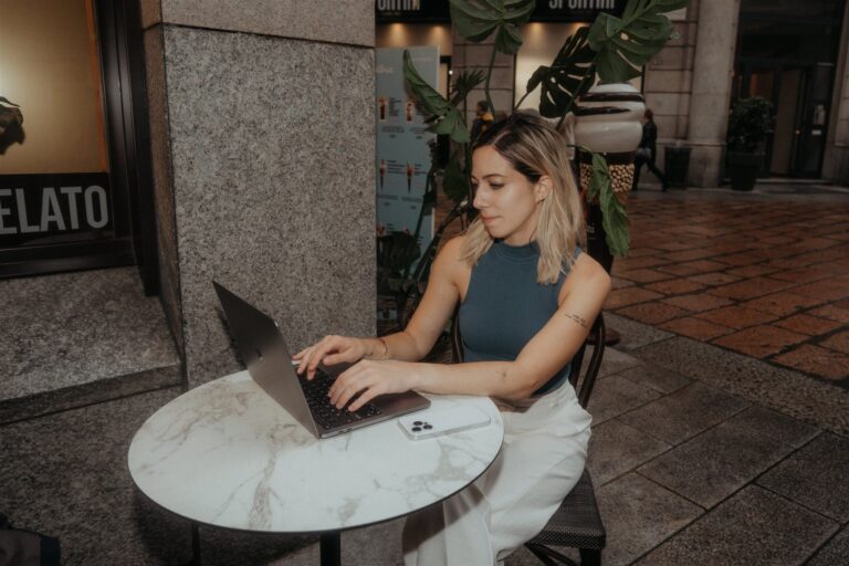 Woman sits at an outdoor cafe in Milan and works on her laptop.