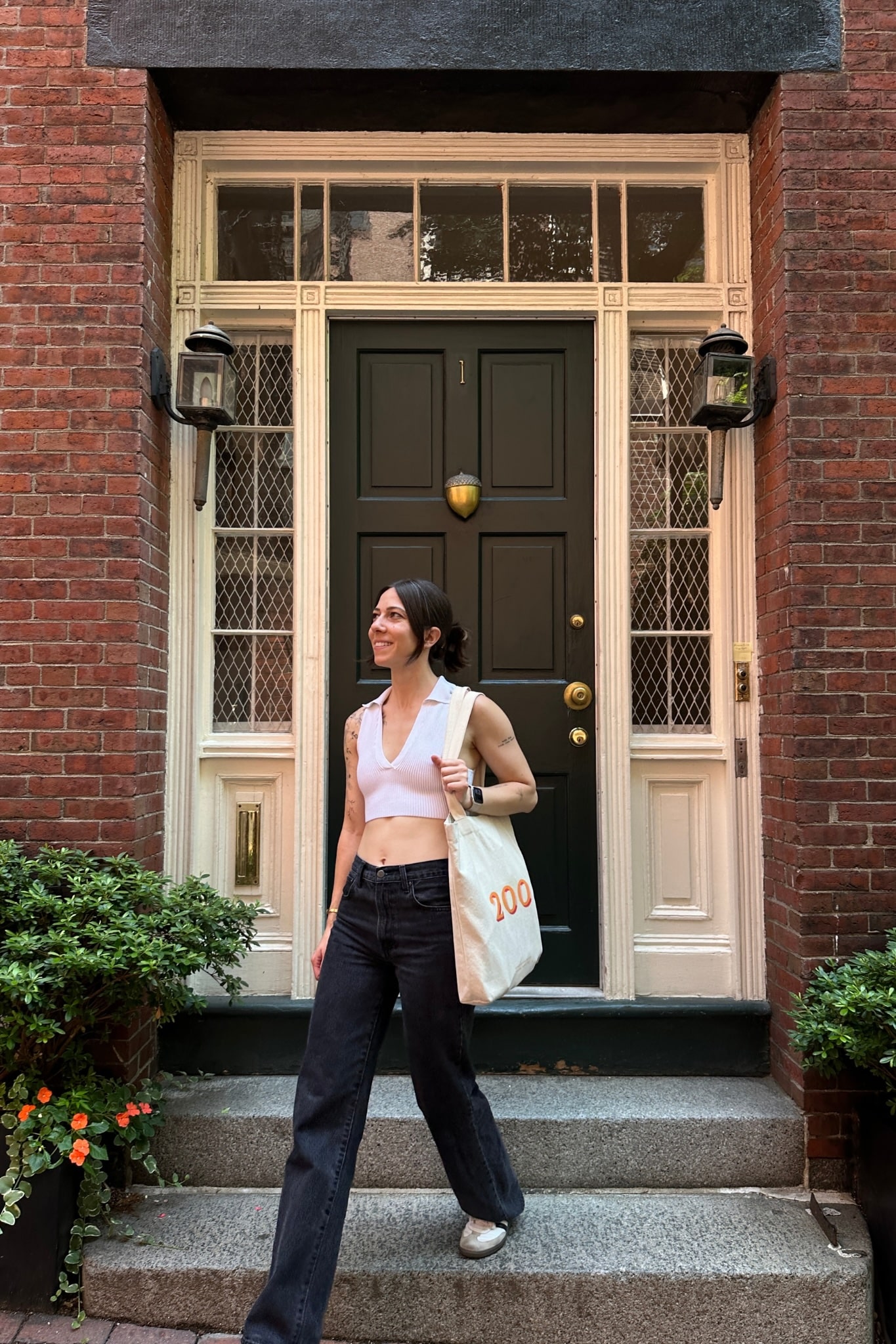 Woman walking down front porch steps with a tote bag on her arm.