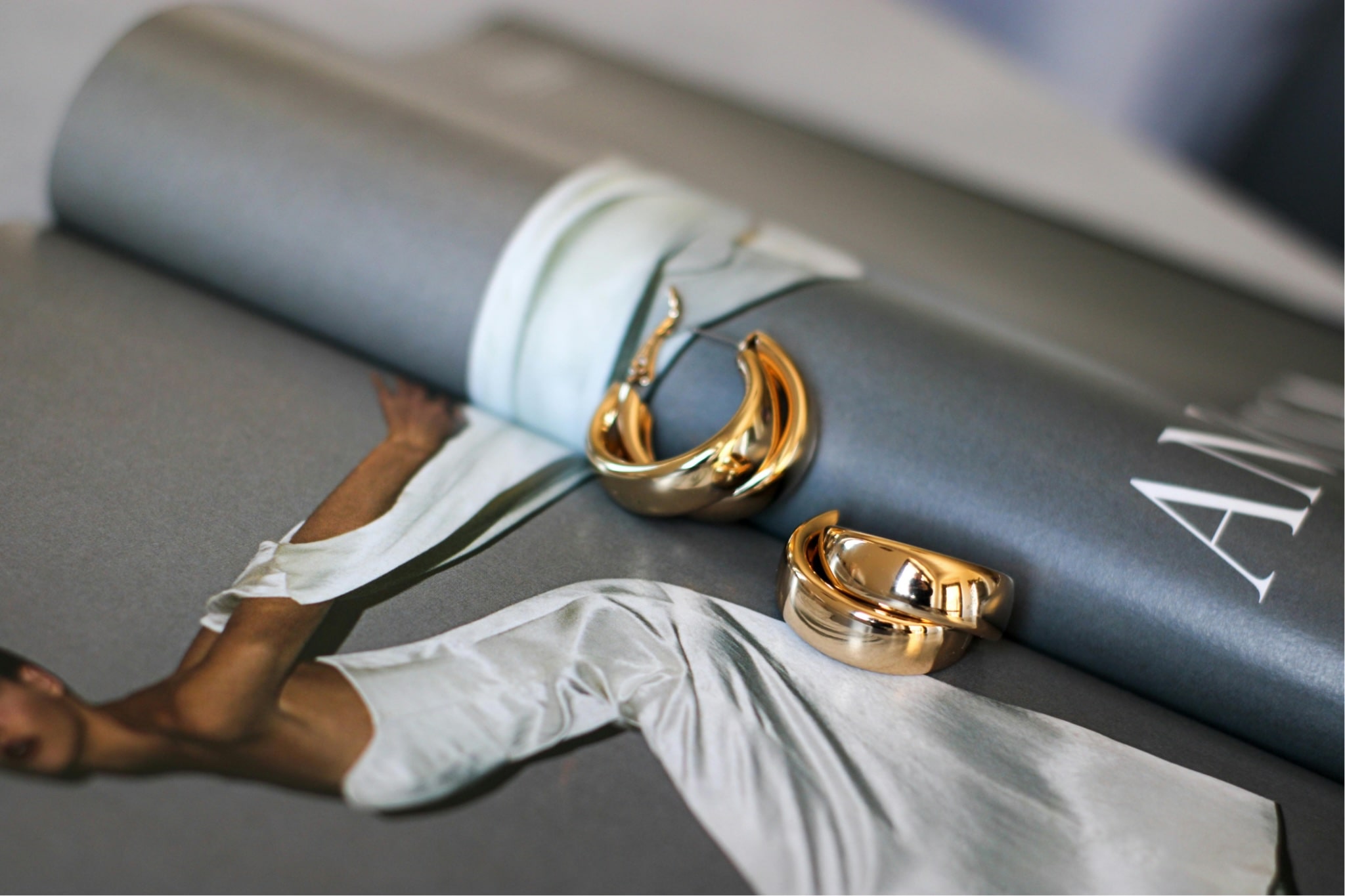 Wedding magazine open with gold hoop earrings lying on top o fit.
